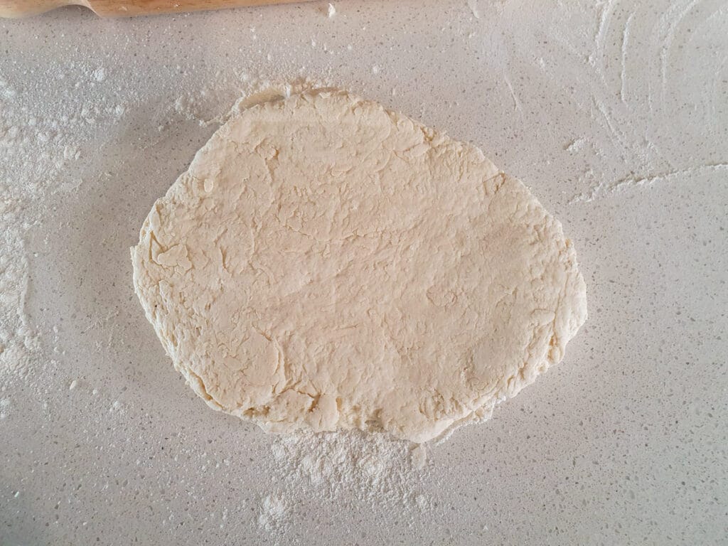 Starting to roll out dough before picking up, re flouring and flipping.
