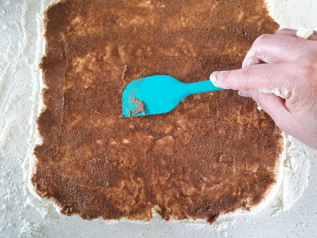 Spreading cinnamon sugar butter over dough.