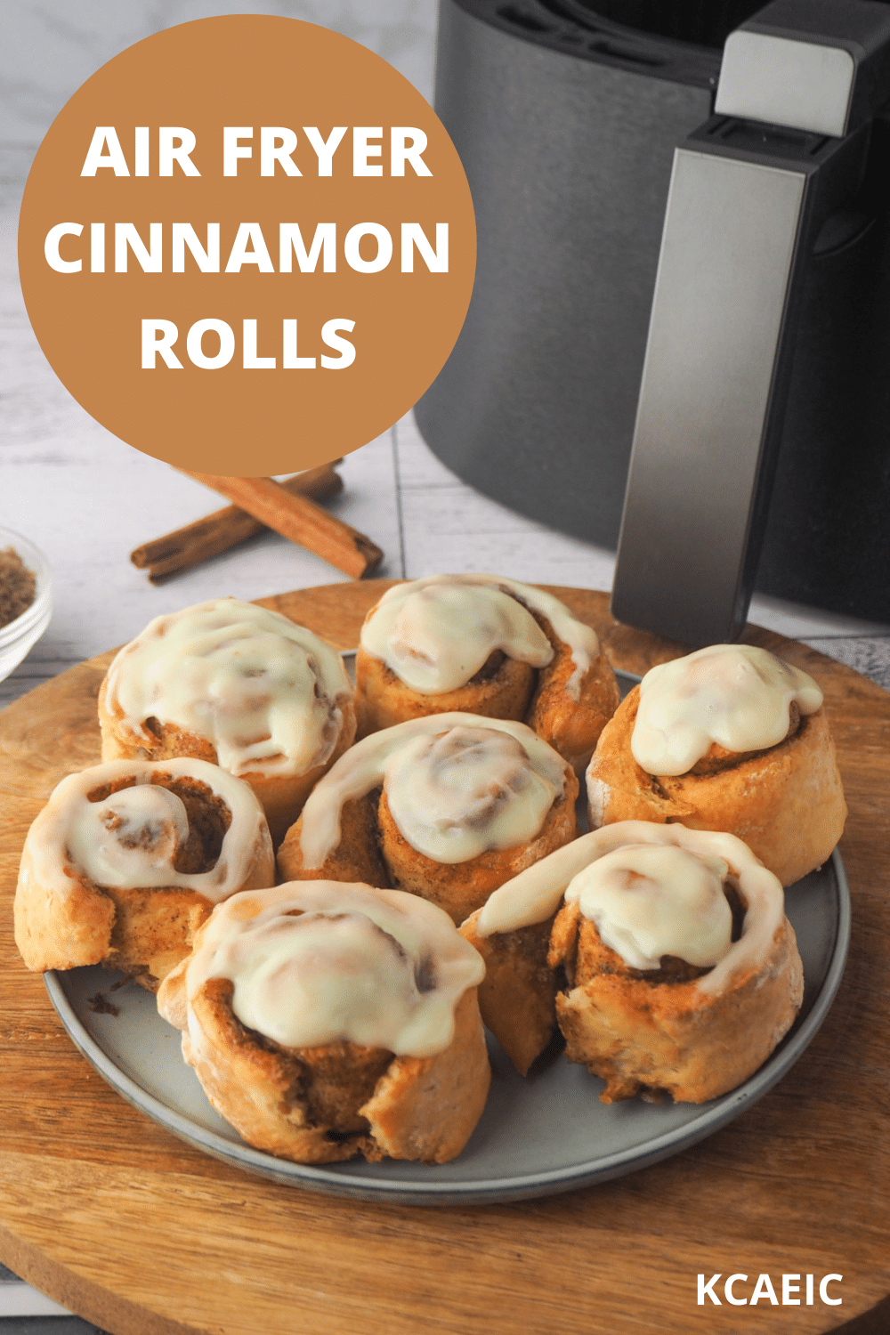 Scrolls on a plate, with air fryer in the background and text overlay, air fryer cinnamon scrolls and KCAEIC.