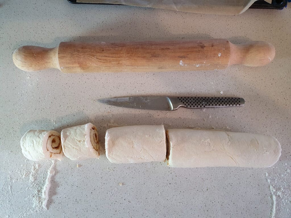 Cutting up scrolls, cut dough in half, then in half, then in half again to get eight scrolls.
