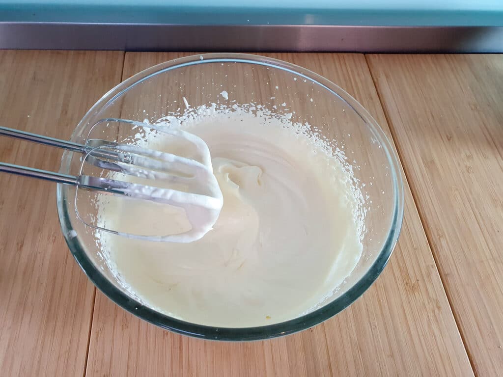 Whipping the cream to soft peaks.