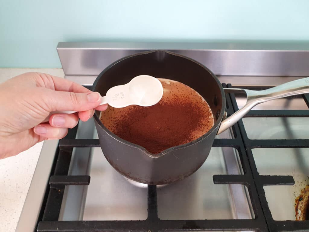 Adding glucose syrup to pot on stove.