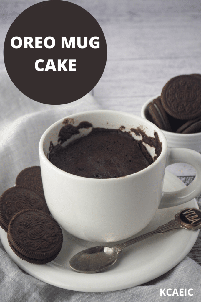 Mug cake on a saucer with a spoon, Oreos on the side and in the background, with text overlay, Oreo Mug Cake and KCAEIC.
