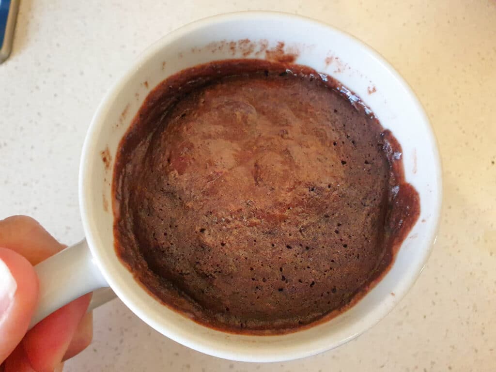 Mug cake showing uncooked batter that needs cooking a bit longer.