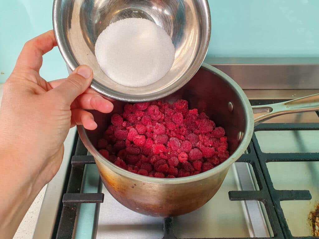 Raspberry Compote 5 Adding sugar to the pot.