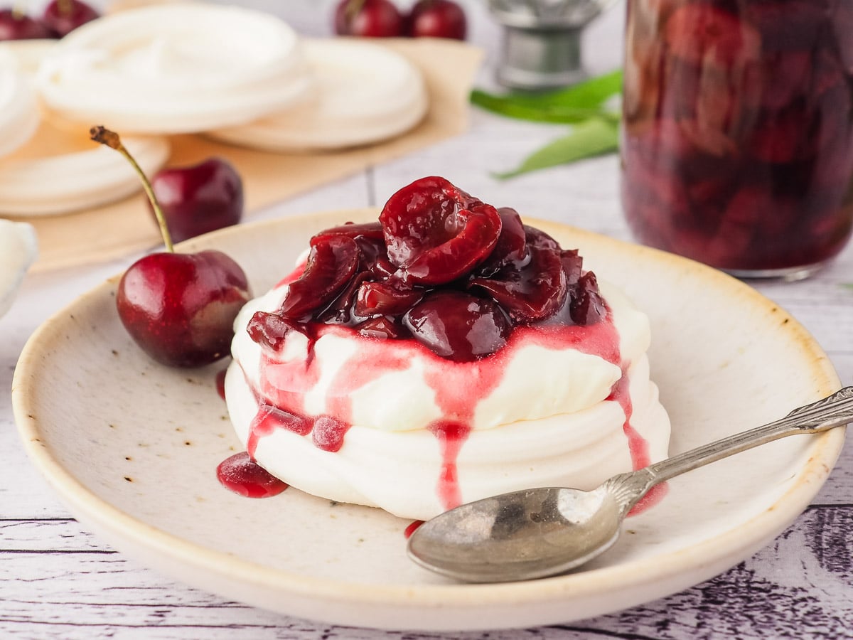 Cherry compote drizzled over meringue nests with cream.