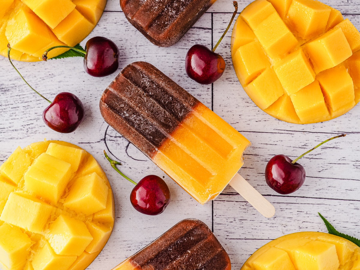 Cherry Mango Popsicles 7 Popsicles surrounded by fresh cherries and mango