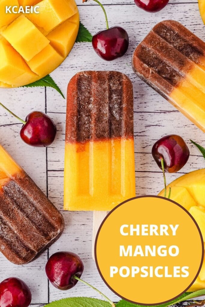 Popsicles surrounded by fresh cherries and mango, with text overlay, cherry mango popsicles and KCAEIC.