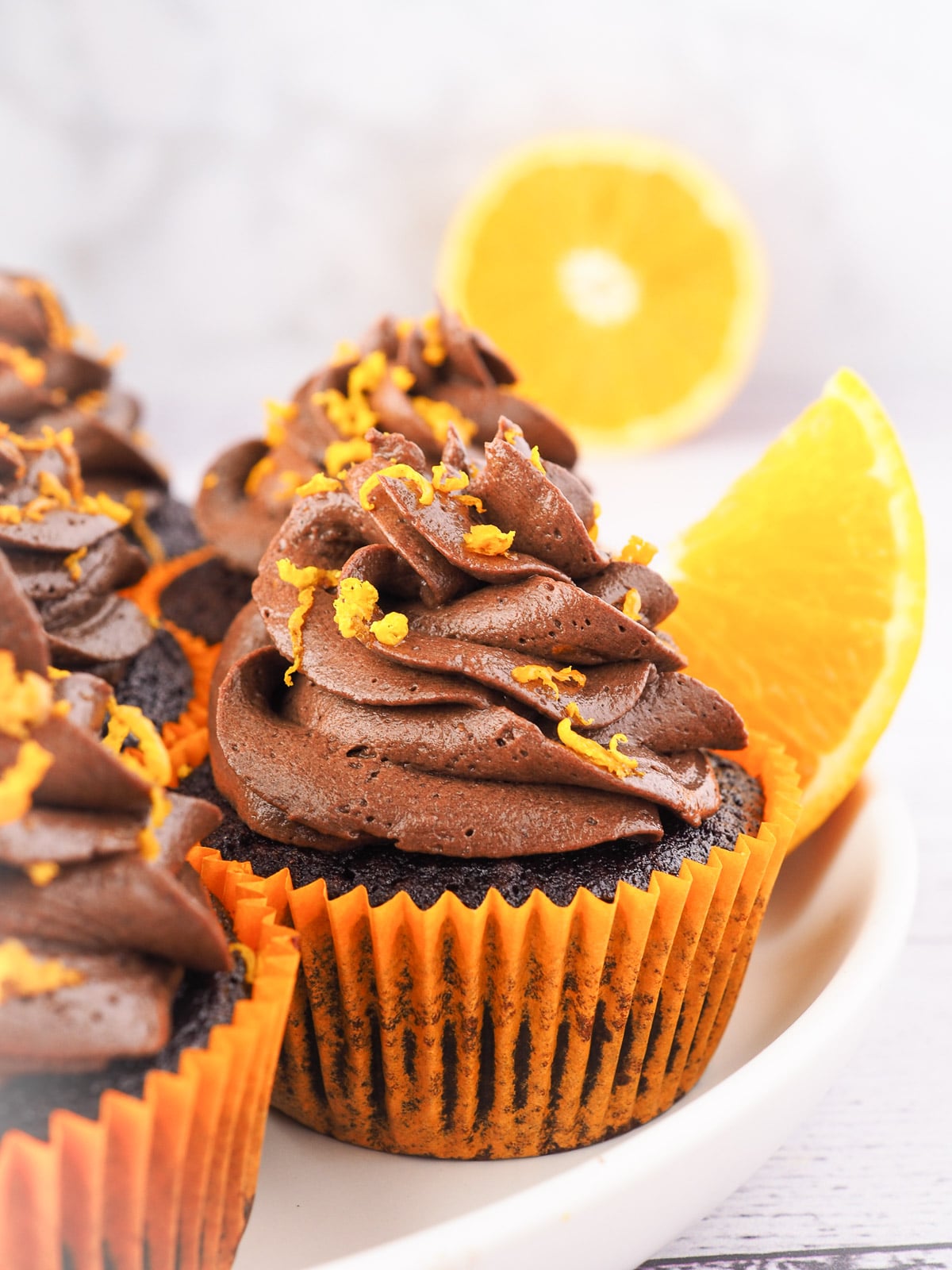 Cupcakes on a plate with fresh oranges in the background.