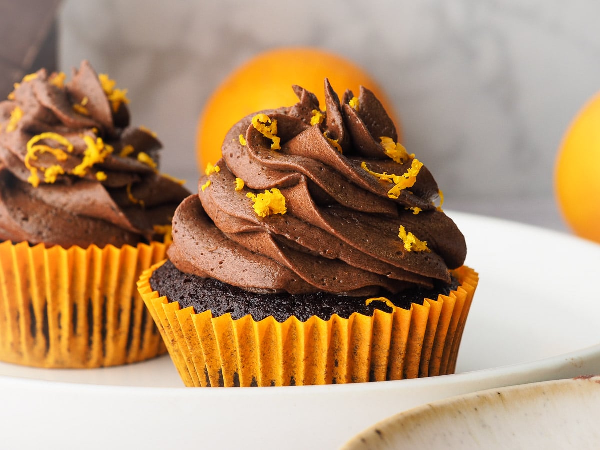Cupcakes on a plate with fresh oranges in the background.