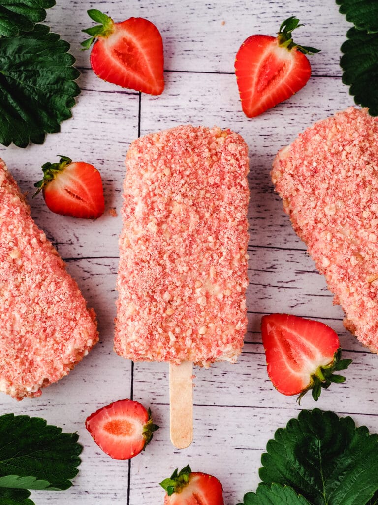 Strawberry shortcake ice cream bar with fresh strawberries and leaves.