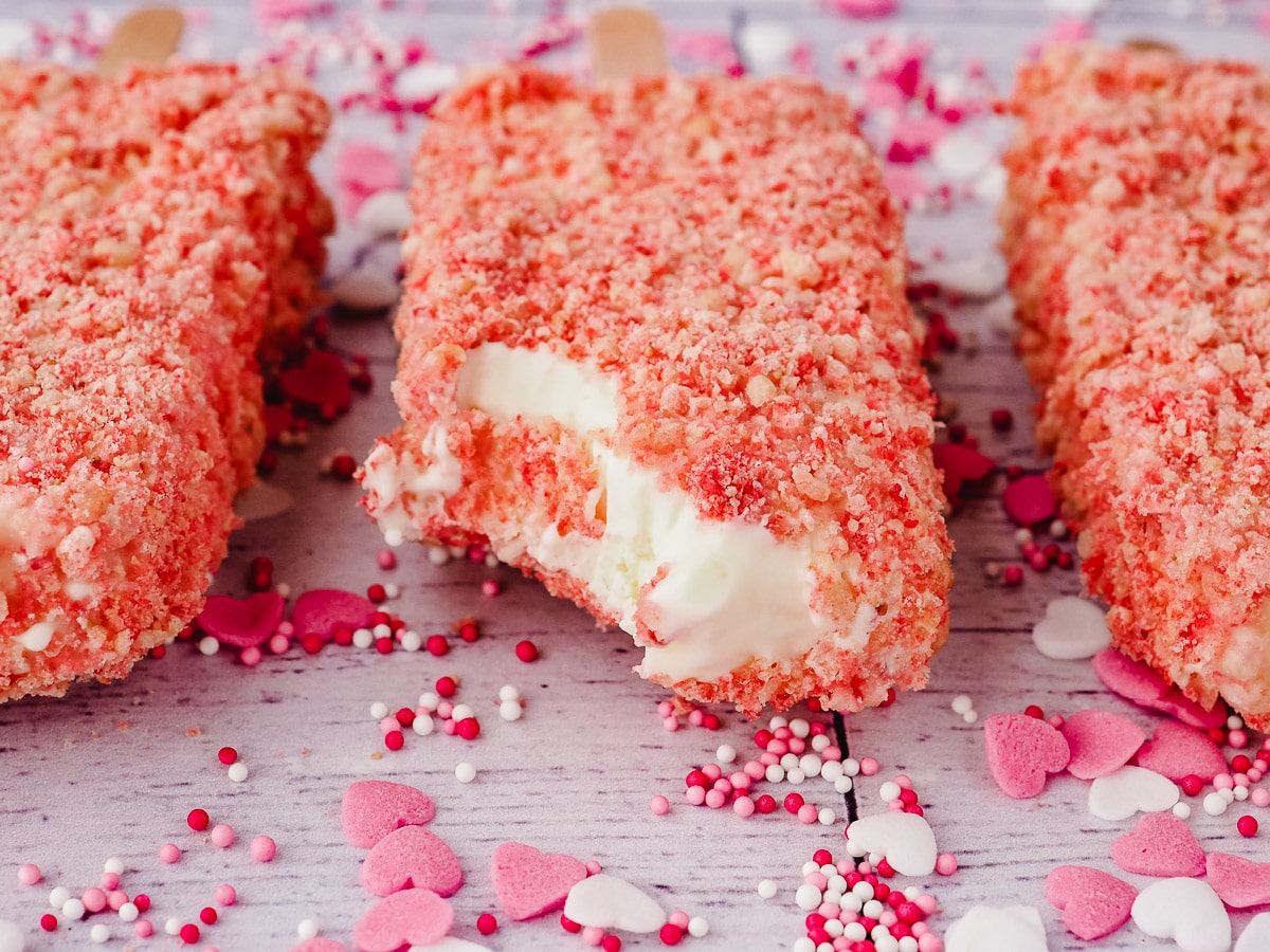 Strawberry Shortcake Ice Cream 9 Ice cream bars with a bite taken out, surrounded by pink and white heart sprinkles.