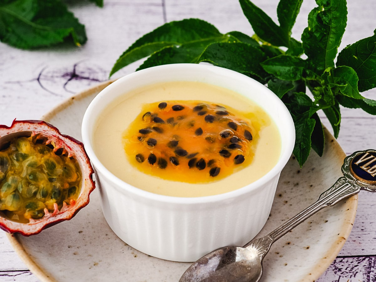 Panna cotta in a ramekin with passion fruit coulis.