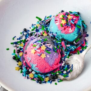 Galaxy Ice Cream 9 Close up two scoops of ice cream with space sprinkles in a bowl with a spoon.