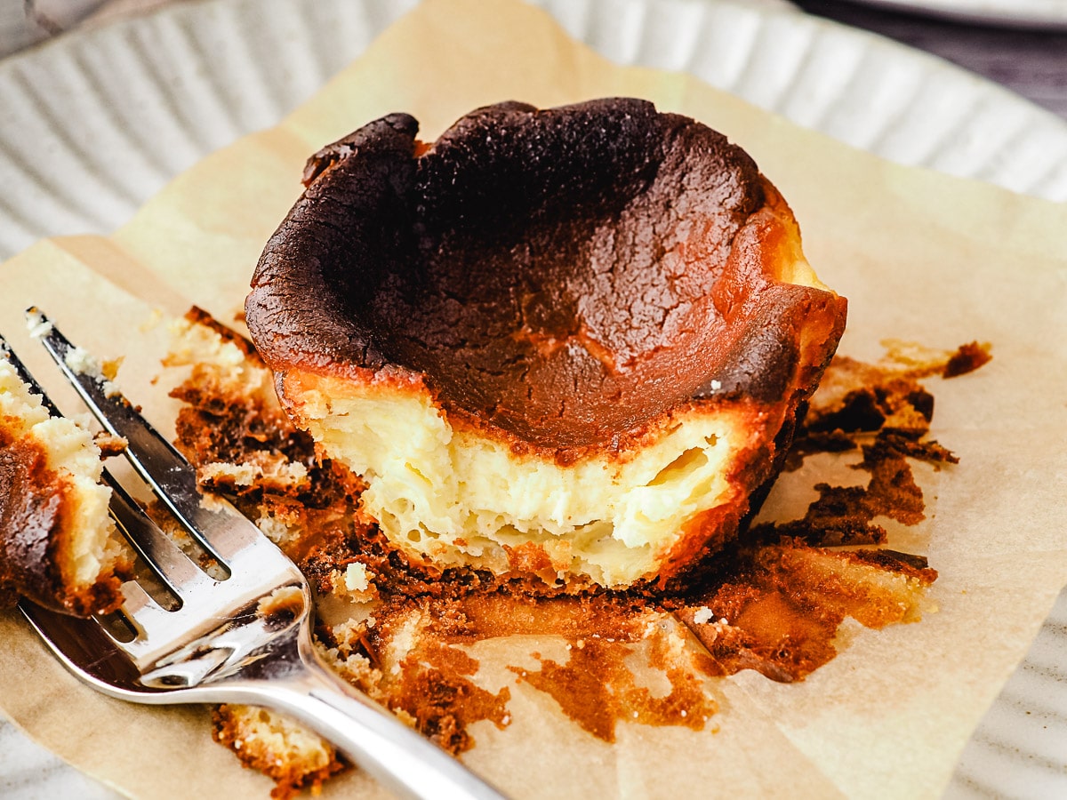 Mini Burnt Cheesecake 8 Close up mini cheesecake on a plate with a piece taken out with a fork.