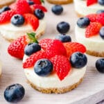 Cheesecakes on a platter with fresh fruit.