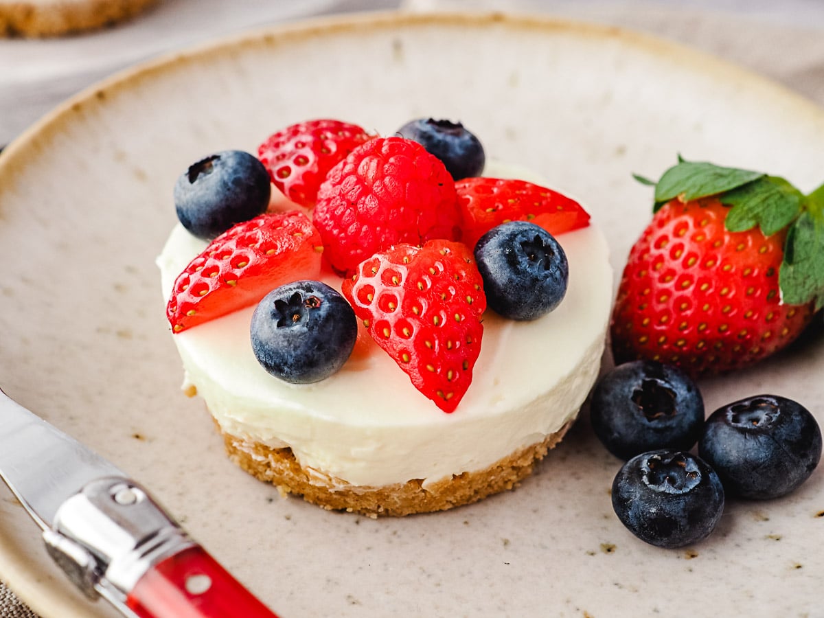 Cheesecake on a plate with fresh berries and a fork.