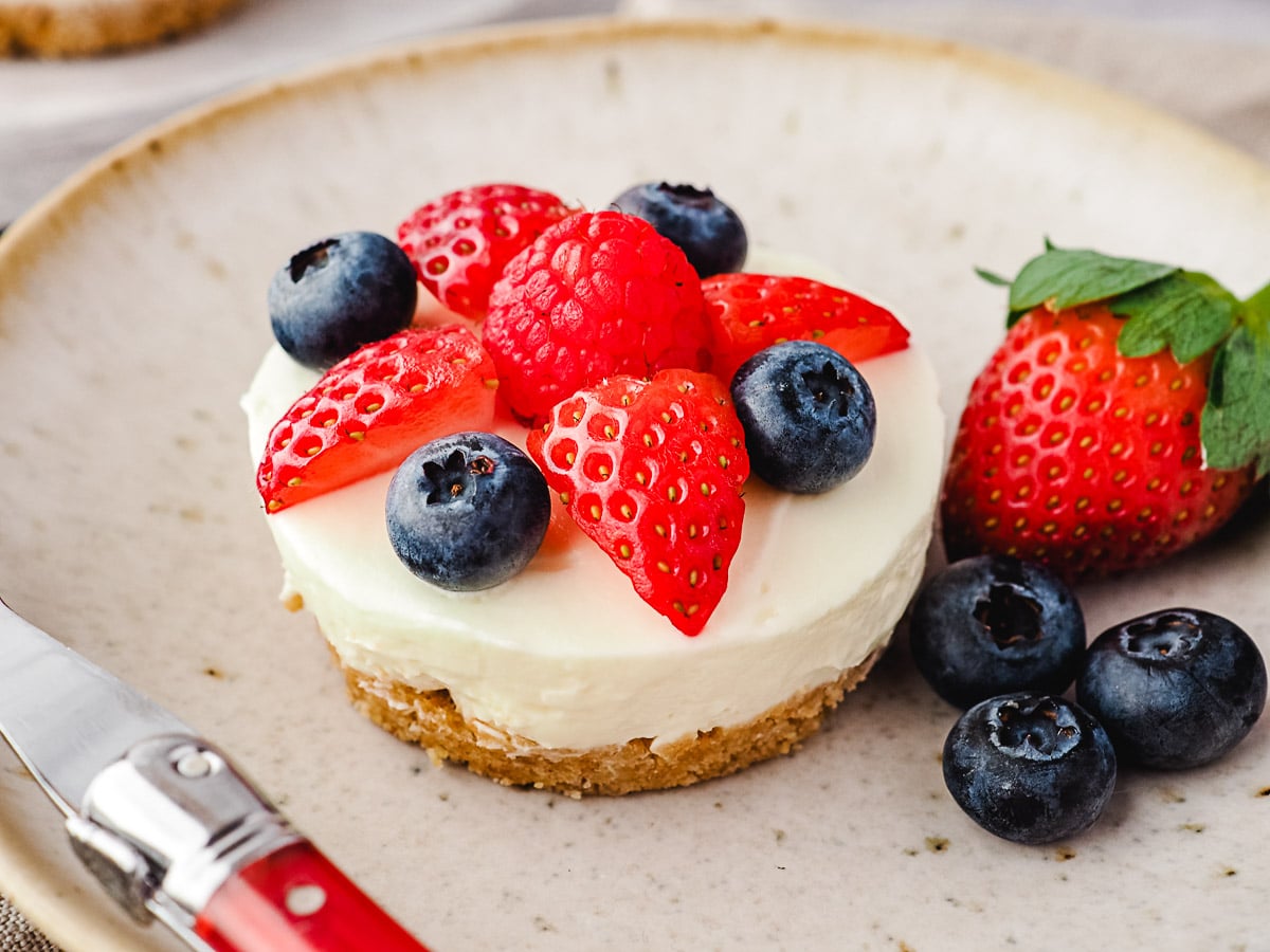 No Bake Mini Cheesecakes 2 Cheesecake on a plate with fresh berries and a fork.