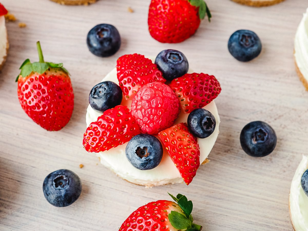 No Bake Mini Cheesecakes 9 Cheesecakes on a platter with fresh fruit.