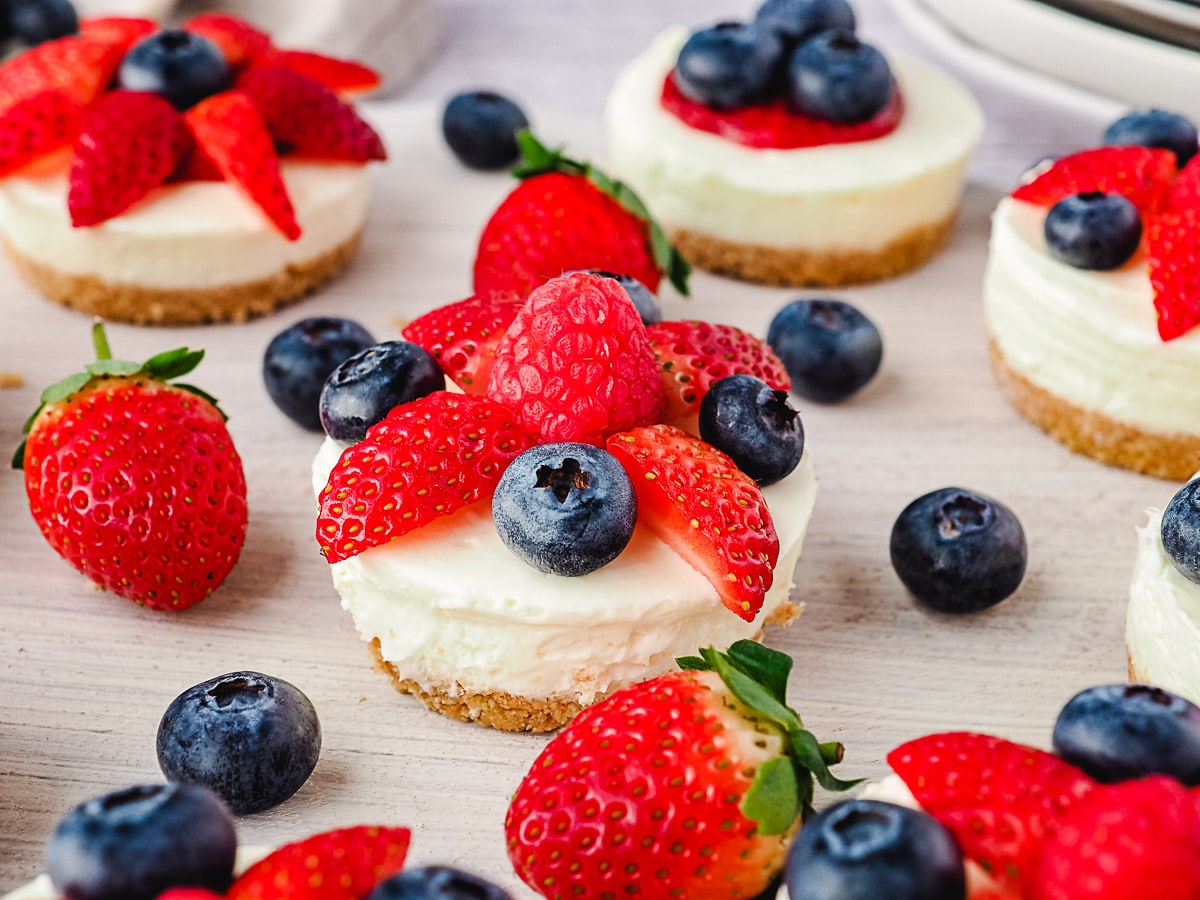Cheesecakes on a platter with fresh fruit.