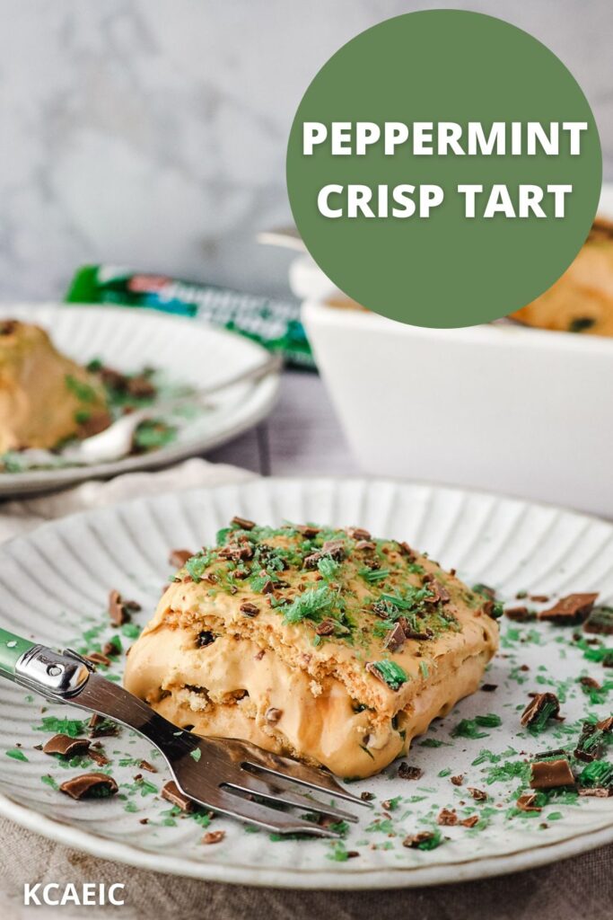 Slice of tart on a plate with a fork, with an extra slice of tart, rest of tart in baking tray and peppermint crisp bars in the background.