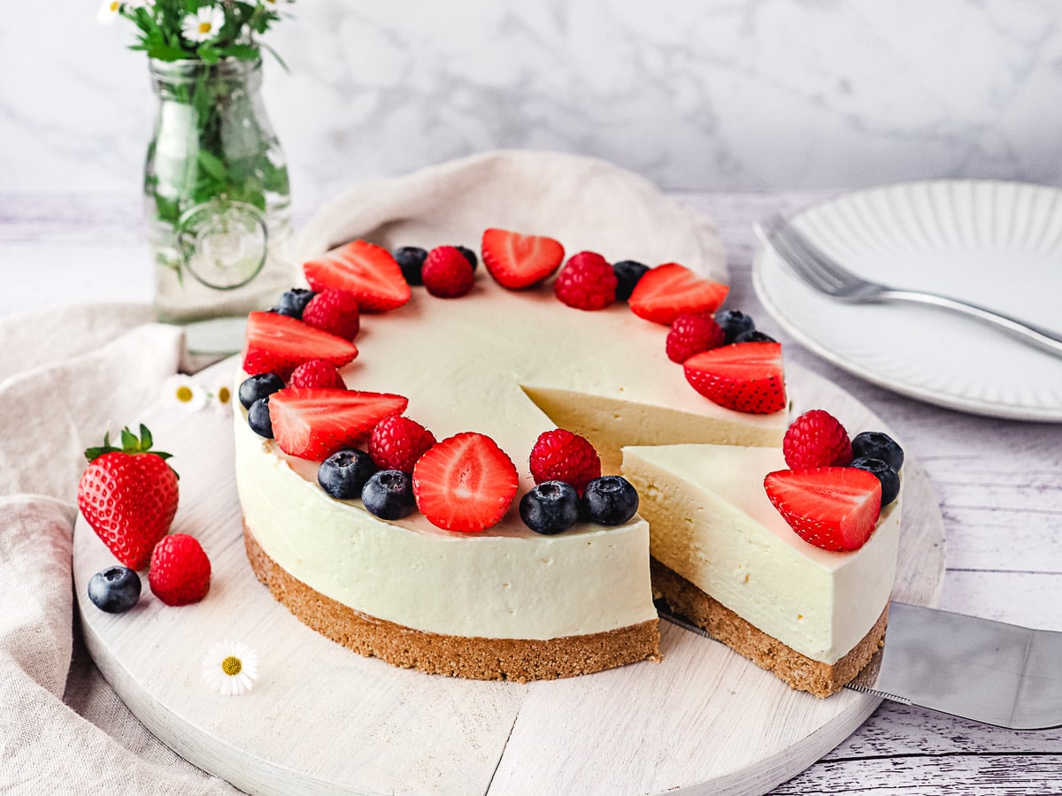 Slicing cheesecake decorated with fresh berries.