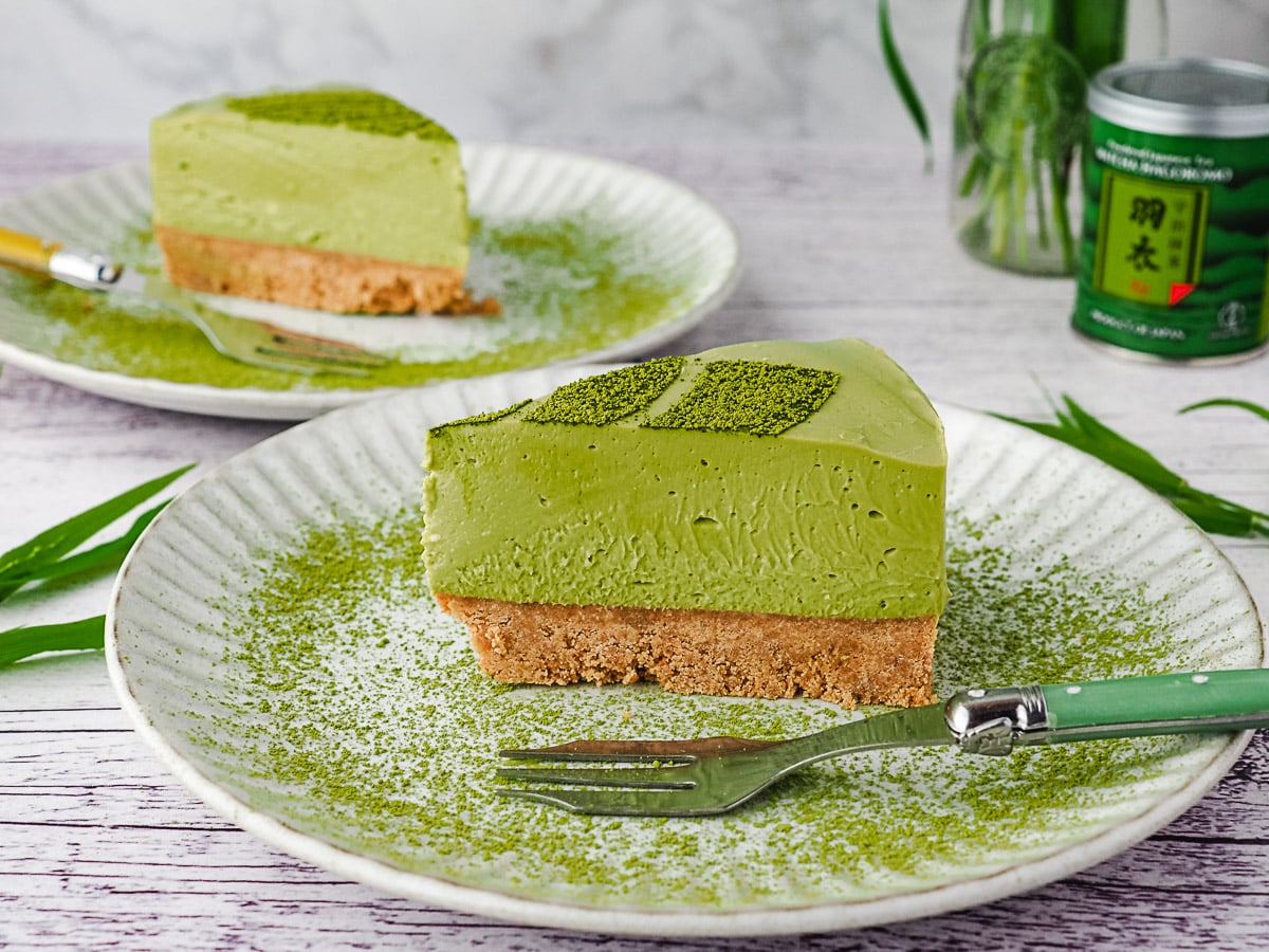 Matcha Cheesecake 8 Slice of cake on a plate with another slice of cake in background.