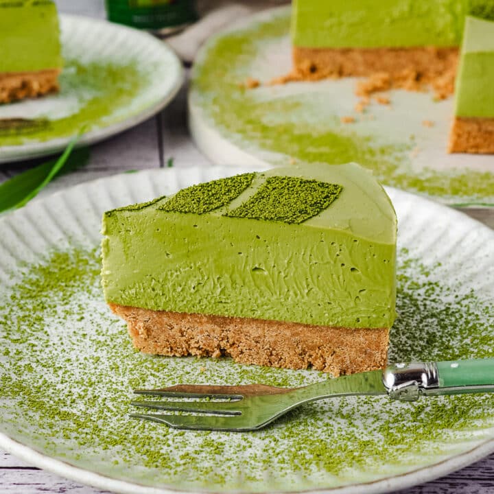 Close up slice of cake o a plate with a fork and matcha dusting.