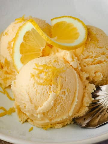 Close up three scoops of ice cream garnished with fresh lemon.