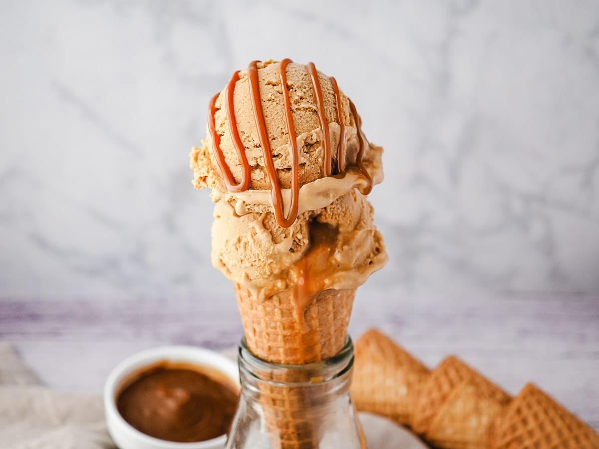 Two scoops of ice cream in a cone with dulce de leche drizzle.