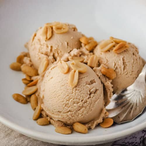 Close up peanut butter ice cream in a bowl with roasted peanuts.