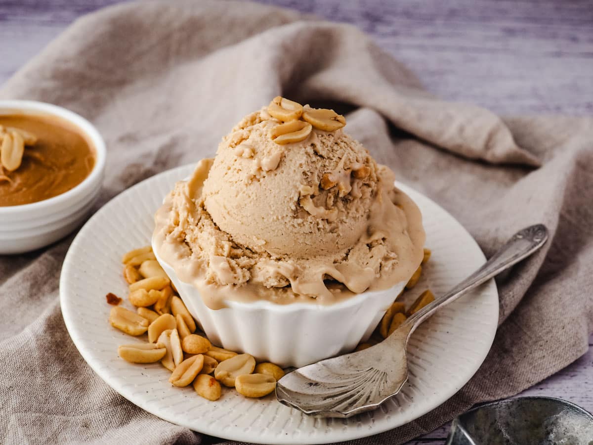Peanut Butter Ice Cream 9 Scoop of ice cream in a bowl with roasted peanuts, and a spoon on the side.