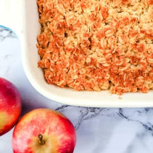 Apple crumble (Apple crisp) 15 Baking dish of apple crumble with fresh apples on the side.