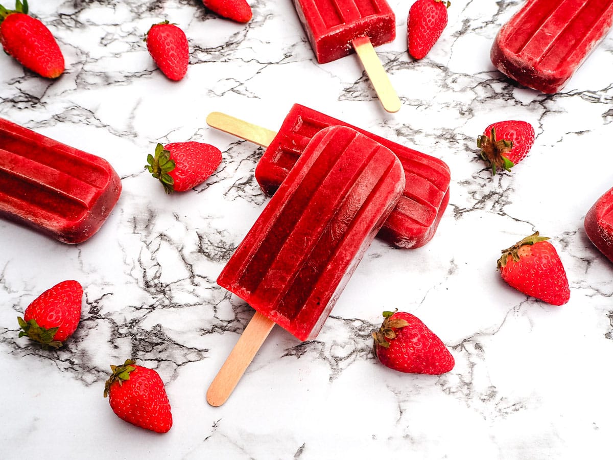 Strawberry balsamic popsicles with fresh strawberries.