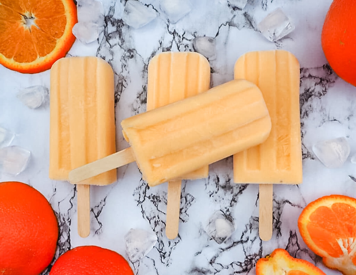 Stack of tangelo creamsicles with fresh tangelos.