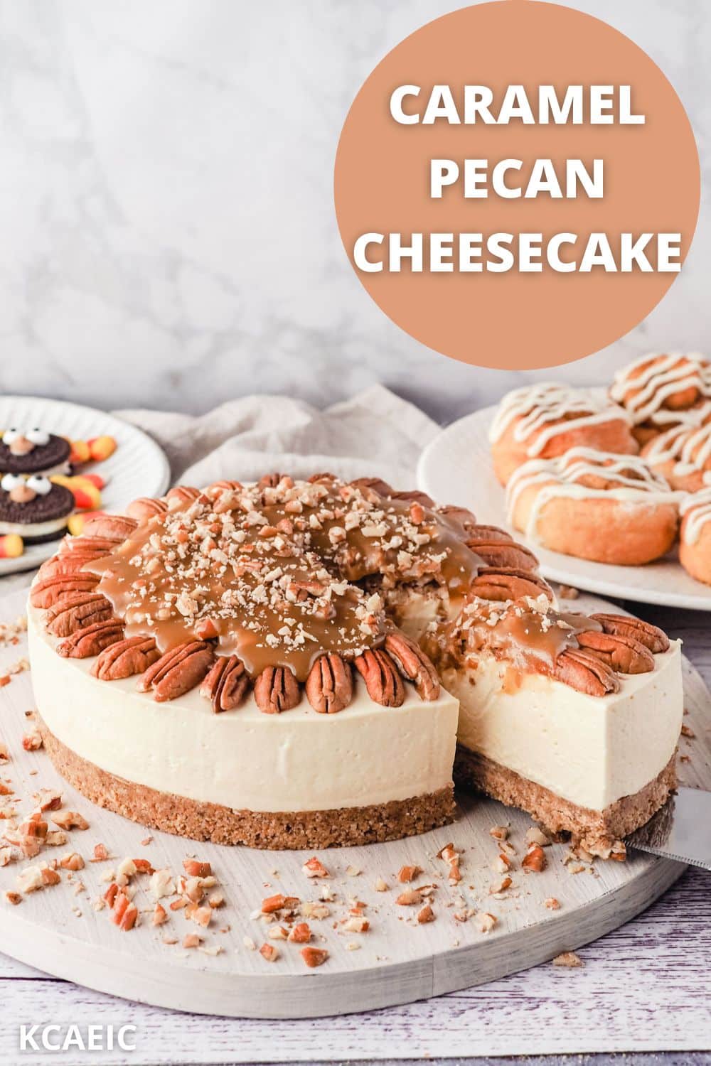 Slicing caramel pecan cheesecake, with air fryer cinnamon scrolls and Oreo turkey cookies for Thanksgiving in the background.