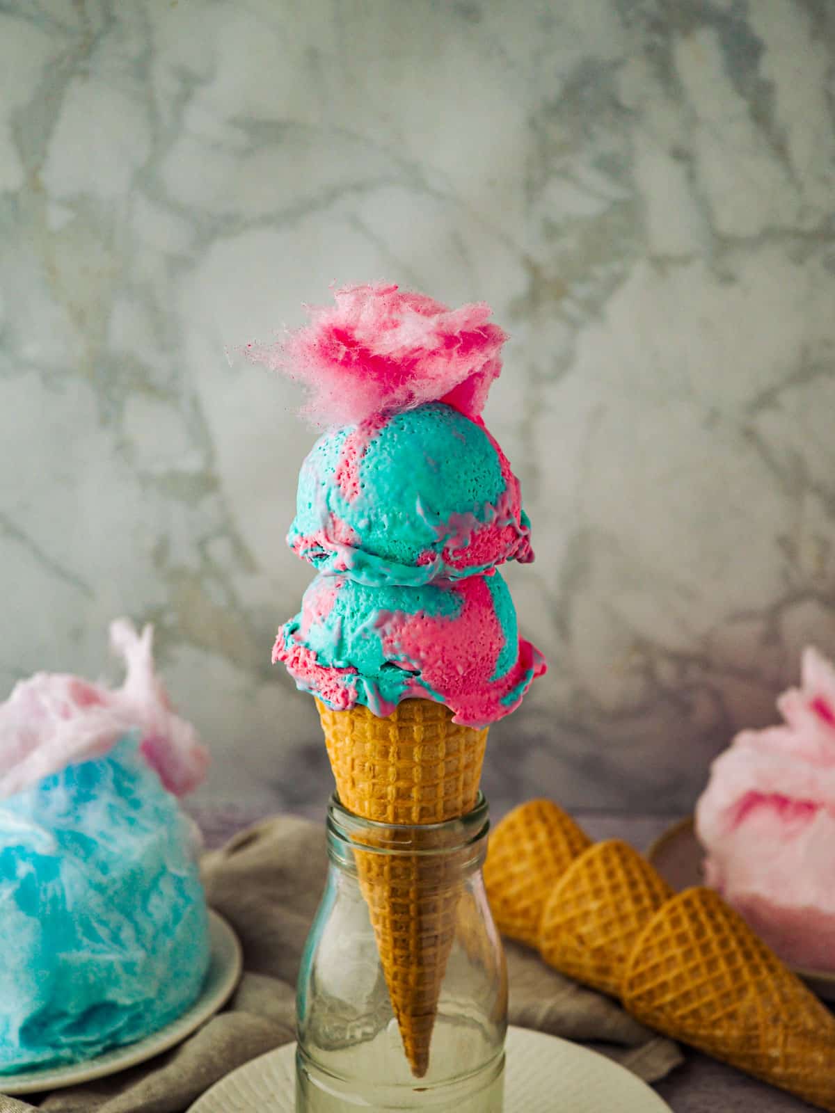 Two scoops of homemade pink and blue cotton candy in a cone.