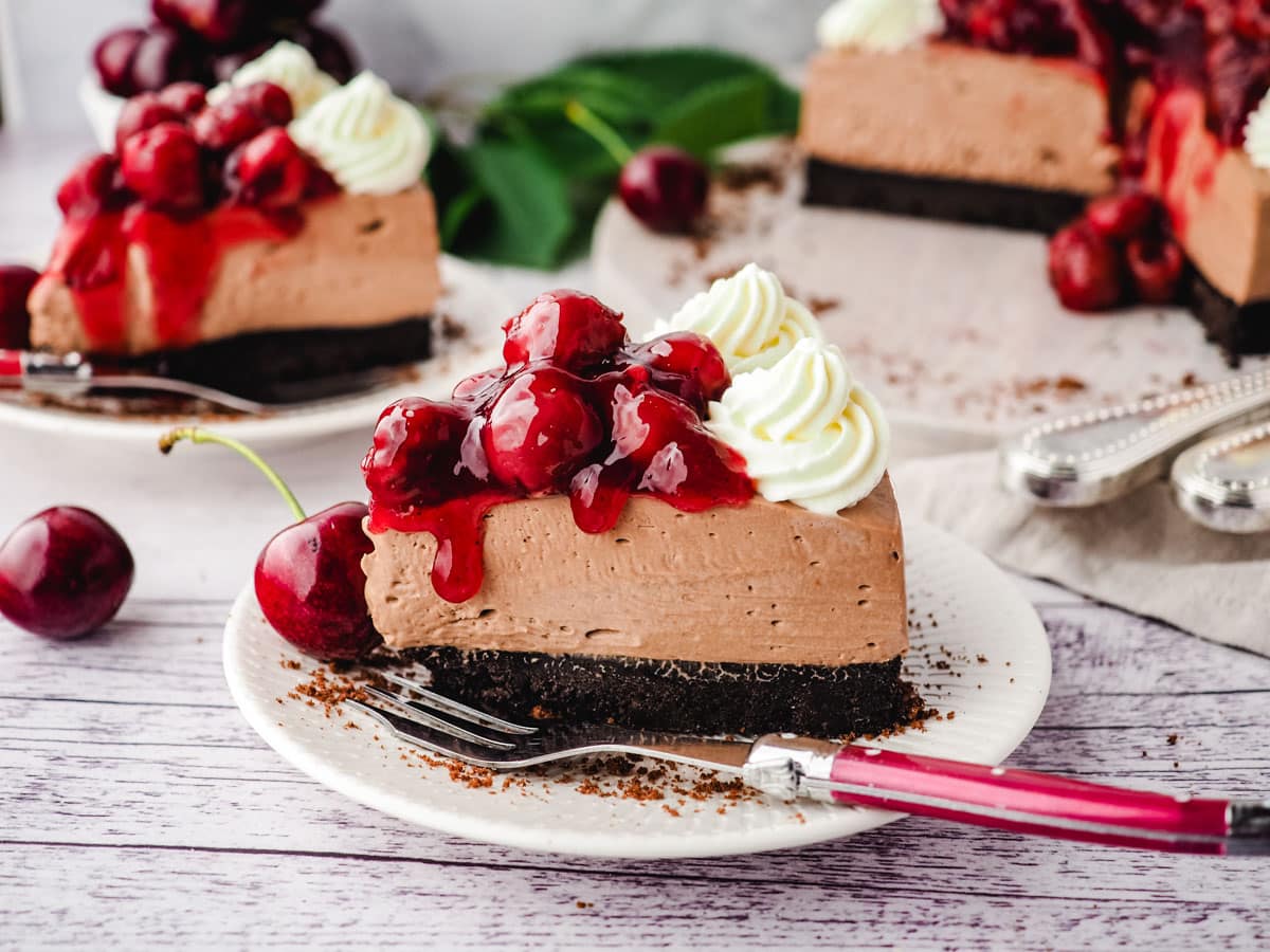 Slice of black forest cheesecake on a plate with a fork.