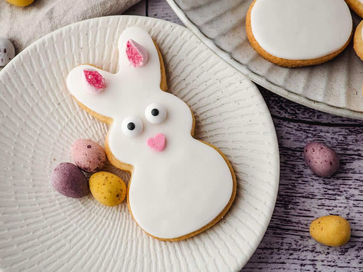 Bunny cookie on a plate with mini eggs.