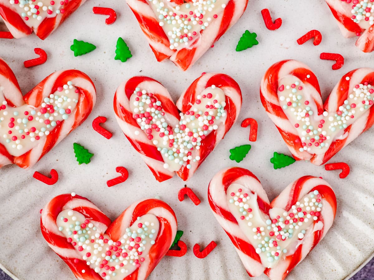Candy cane hearts on a plate with Christmas sprinkles.