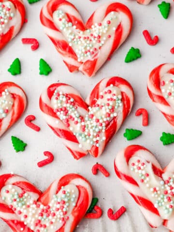 Candy cane hearts on a plate with Christmas sprinkles.