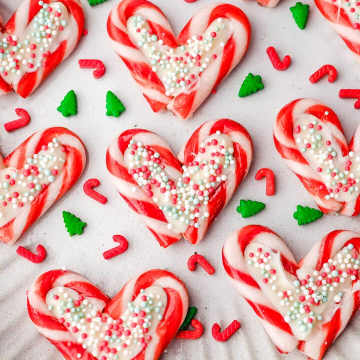 Candy cane hearts on a plate with Christmas sprinkles.