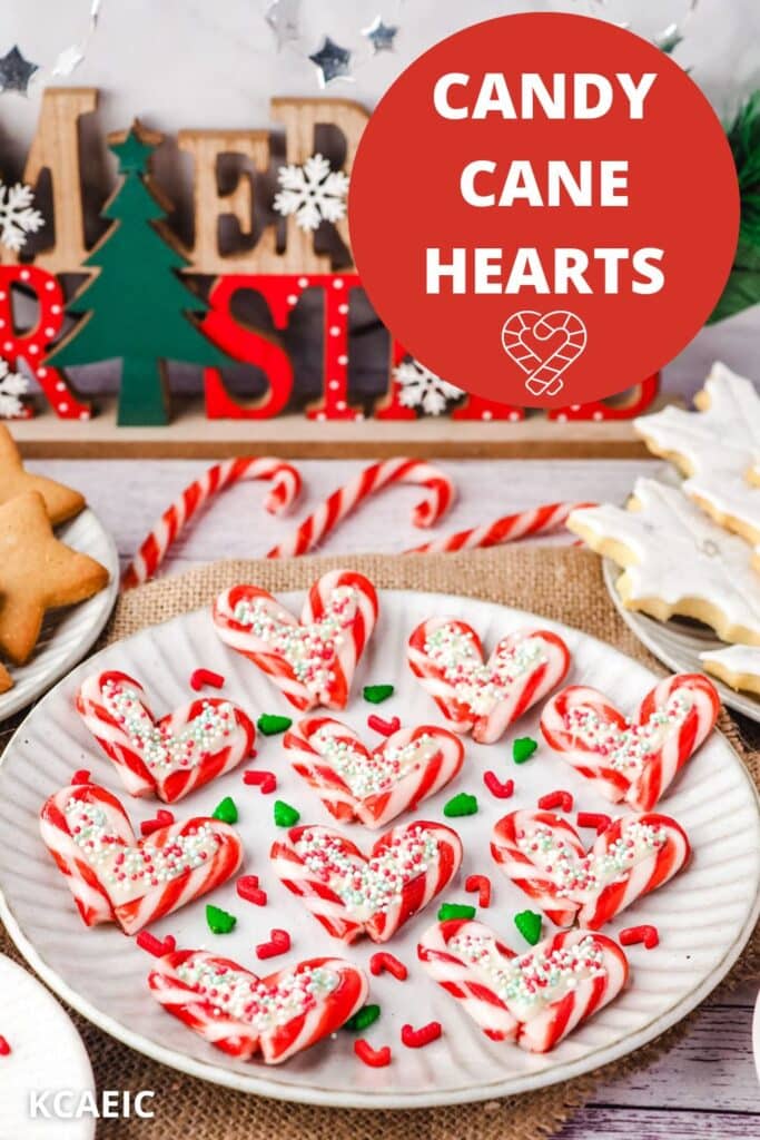 Candy cane hearts on a plate with sprinkles, on a Christmas dessert table.