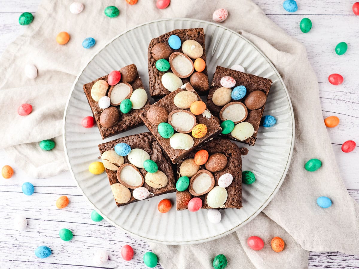 Easter brownies on a plate, surrounded by extra Easter eggs.