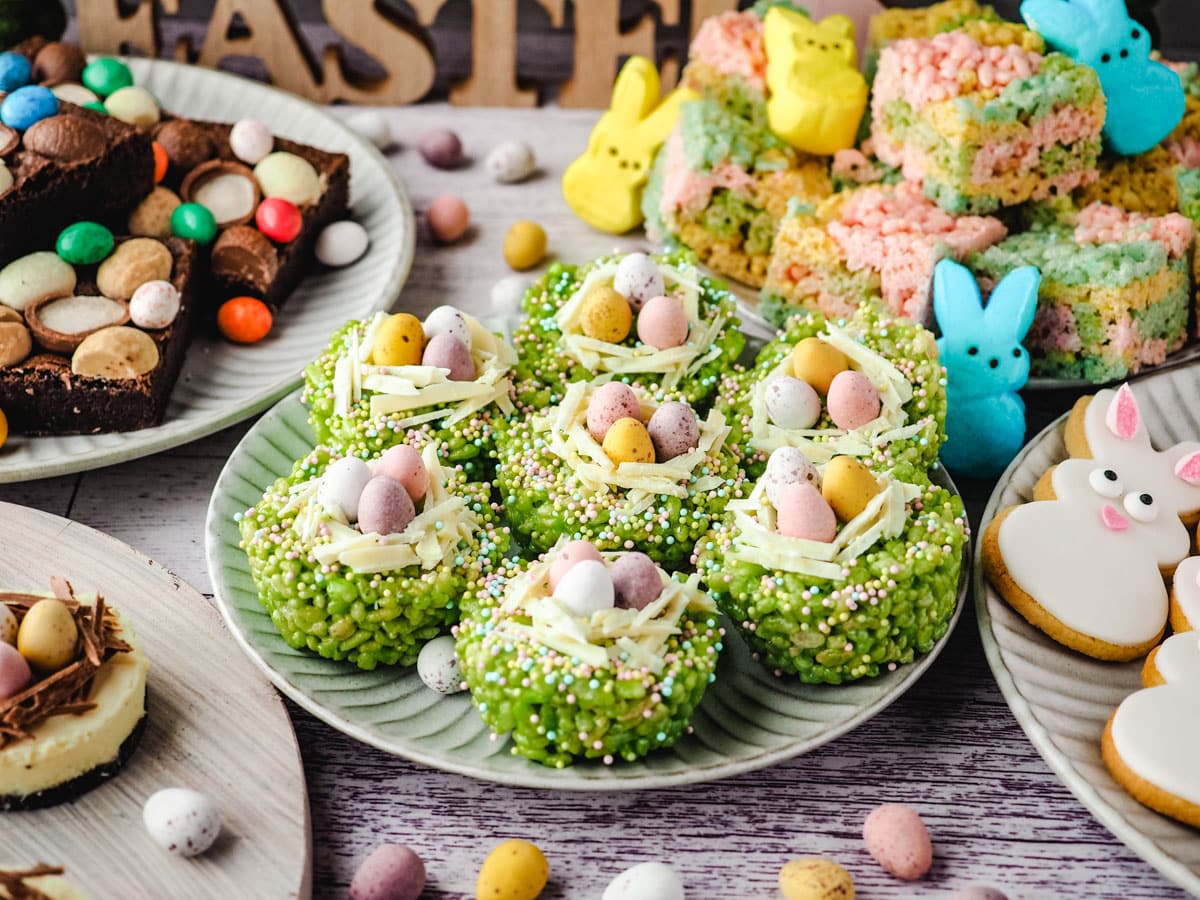 Easter rice krispie treats on a plate surrounded by Easter desserts and Easter decorations.