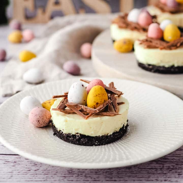 Mini egg cheesecake on a plate with extra mini eggs on the side.