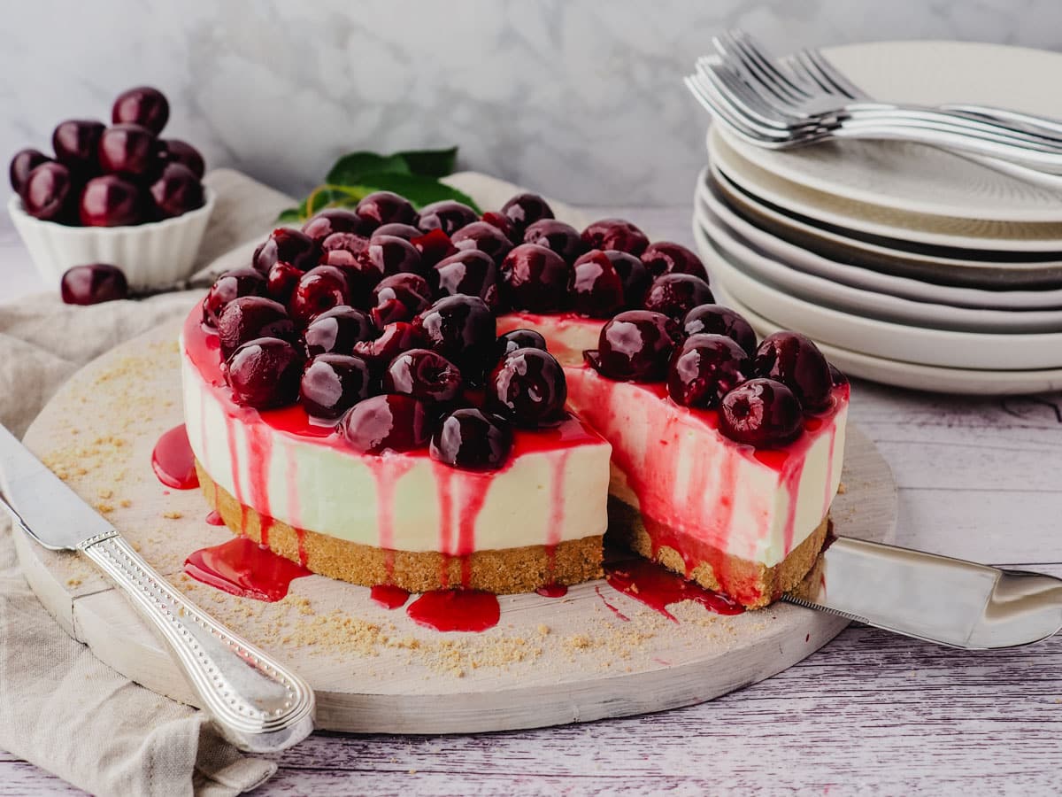 Serving a slice of cherry cheesecake on a serving platter.