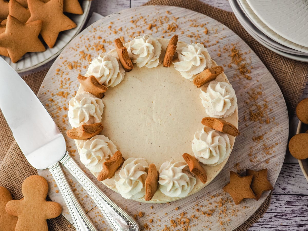 Top down view of gingerbread cheesecake with serving ware on the side, surrounded by gingergread.