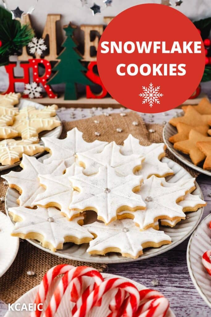 Snowflake cookies on a plate surrounded by Christmas desserts and Christmas decorations.