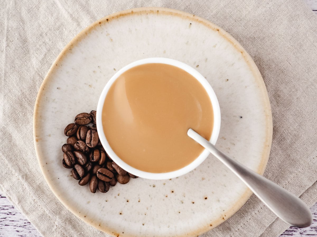 Coffee Sauce 2 Coffee sauce in a bowl with a spoon and coffee beans on the side.